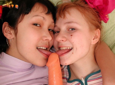Young looking girls share a double ended dildo during interracial lesbian sex
