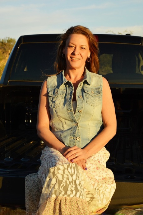Mature cowgirl Emily Rain lifts her skirt up and shows her meaty pussy outside